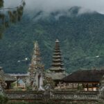 A beautiful temple in Bali with mountains and lush greenery in the background, showcasing unique architecture.