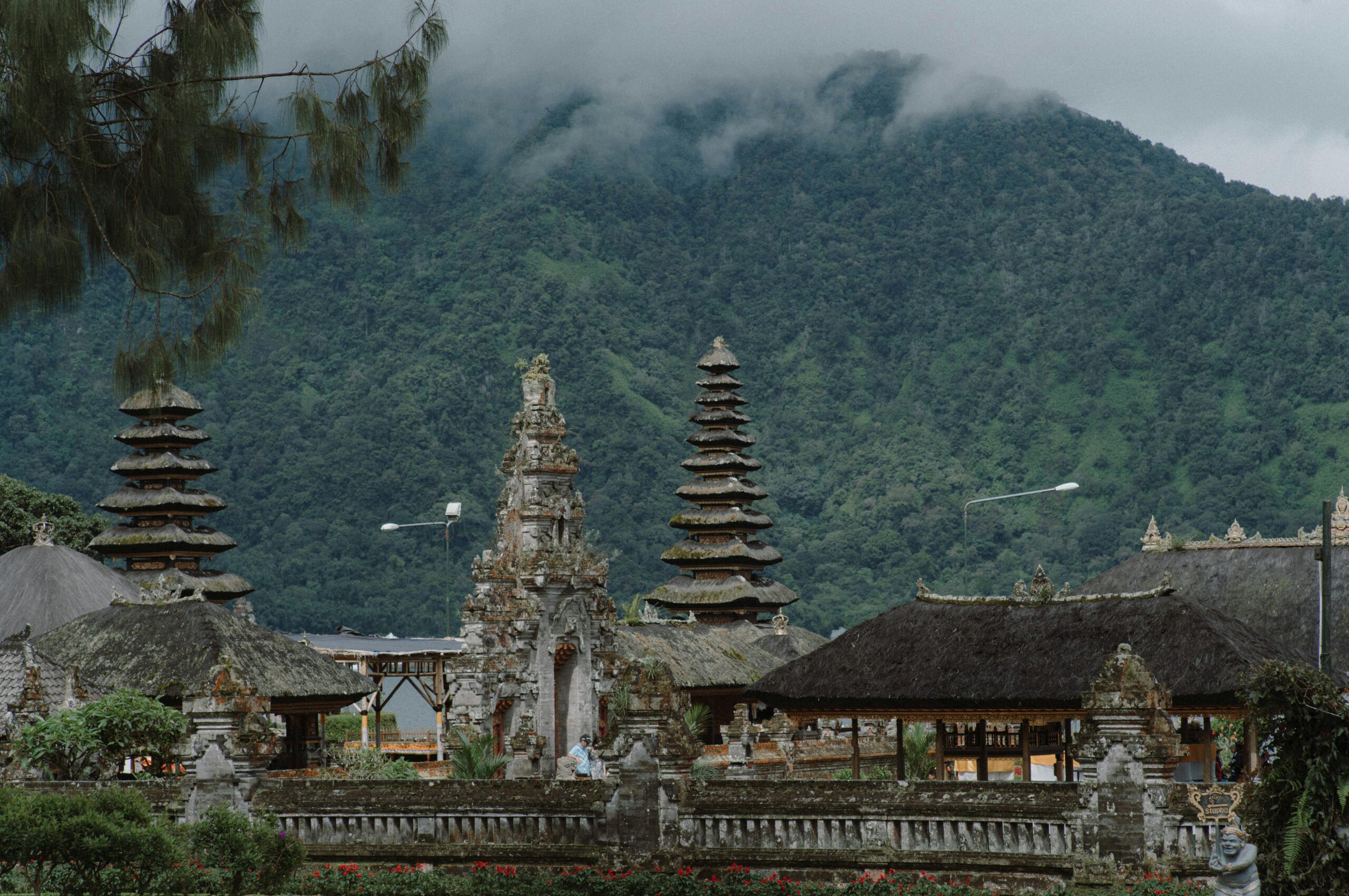 A beautiful temple in Bali with mountains and lush greenery in the background, showcasing unique architecture.